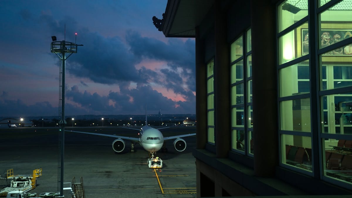 Modern plane parking on stand near assigned gate in modern airport terminal at night