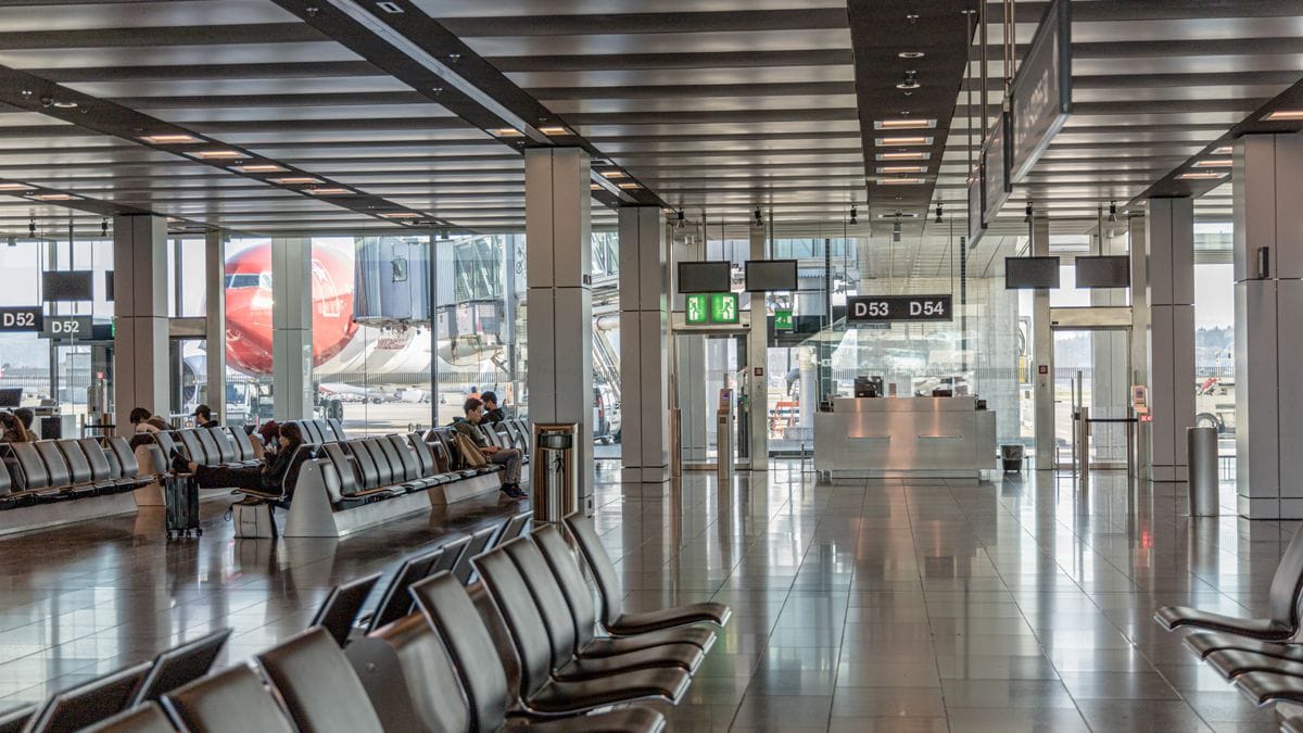 Spacious airport terminal with empty seating and a view of an airplane through large glass windows.